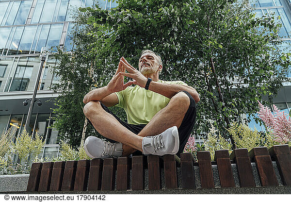 Man with hands clasped meditating on bench