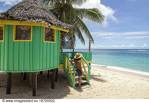 Man with hat  next to turquoise beach hut  during sunny day  Samoa
