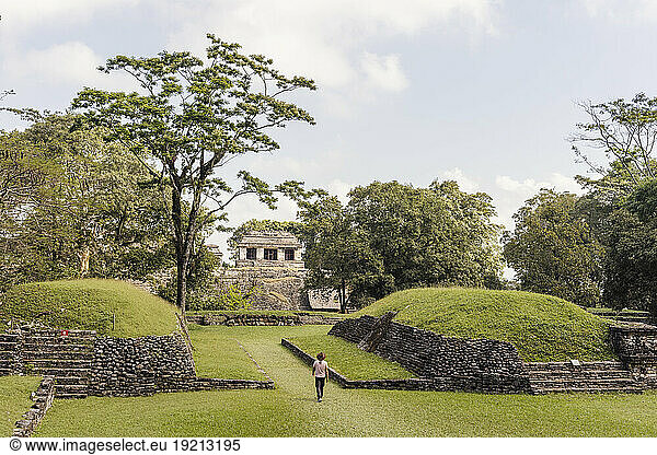 Man with hat walking through Mayan ruins
