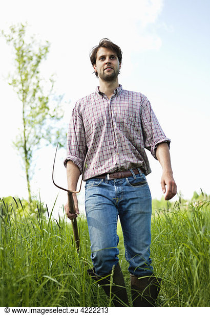 Man with hayfork in high grass