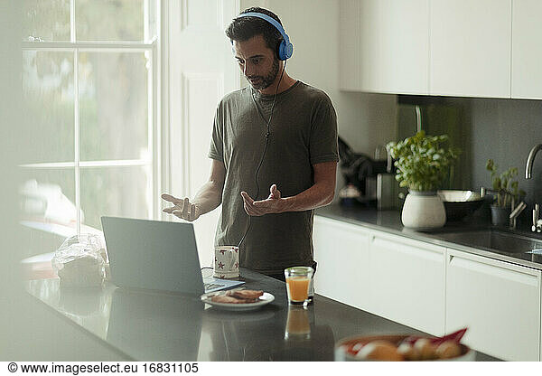 Man with headphones working from home video conferencing at laptop