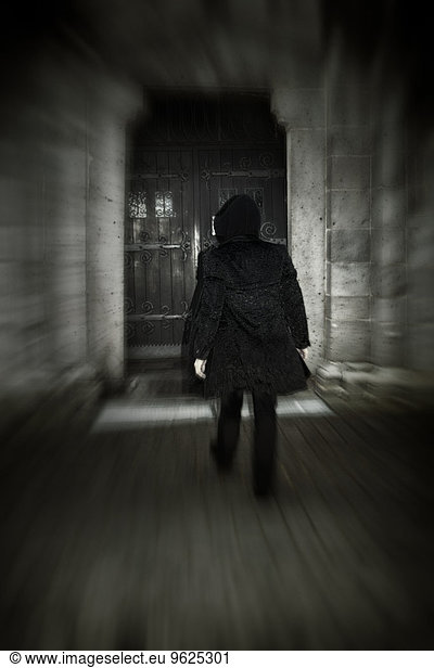 Man with hooded jacket walking towards old door