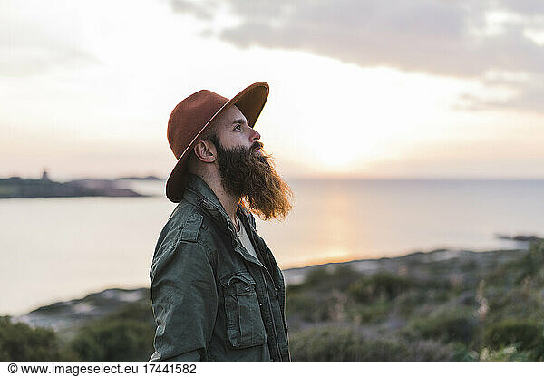 Man with long beard wearing hat during sunset