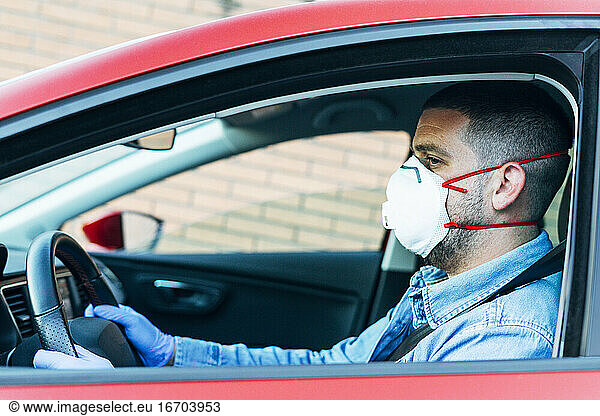 Man with mask and gloves driving a car. Driving and COVID-19 Concept.