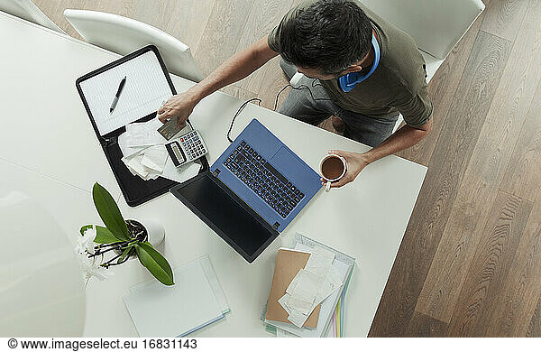 Man with receipts paying bills at laptop