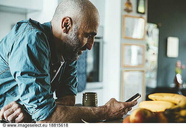 Man with shaved head using smart phone at home
