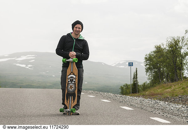 Man with skateboard  standing on road