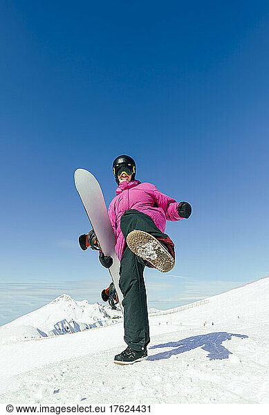 Man with snowboard kicking standing on snowy mountain
