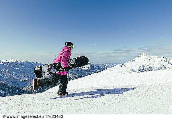 Man with snowboard running on snowy mountain