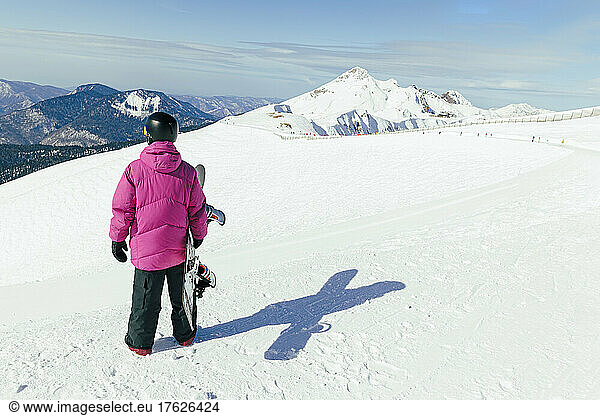 Man with snowboard standing on snowcapped mountain