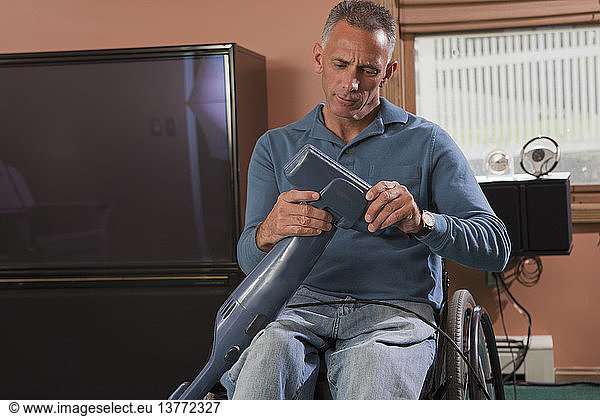 Man with spinal cord injury in a wheelchair cleaning a vacuum cleaner