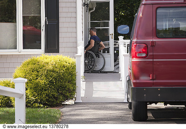 Man with spinal cord injury in a wheelchair going up home ramp