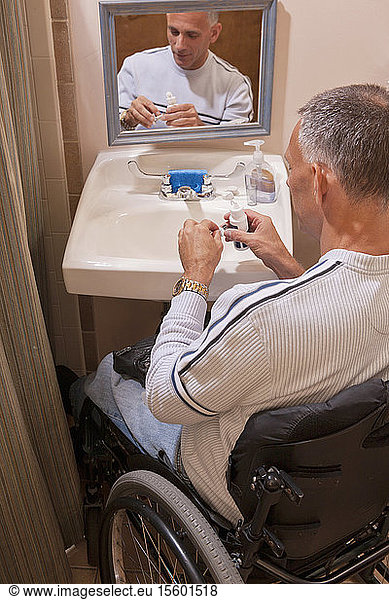 Man with spinal cord injury in an accessible bathroom putting in contact lenses
