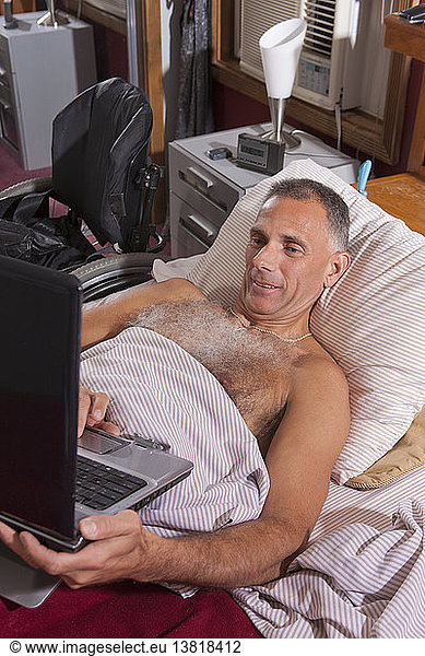 Man with spinal cord injury in the bed using his laptop