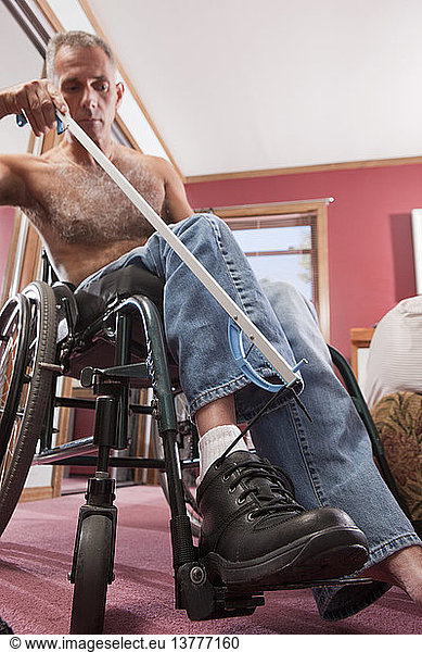 Man with spinal cord injury untying his shoes with an extension tool