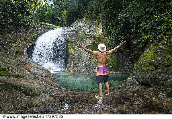 Man with straw hat on beautiful crystal clear water rainforest pool