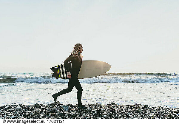 Man with surfboard running on beach