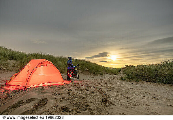 Man with Touring Bicycle Camping on Beach under the Full Moon