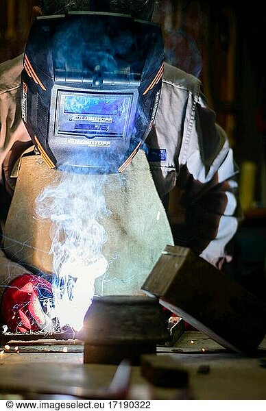 Man with welding mask in a workshop.