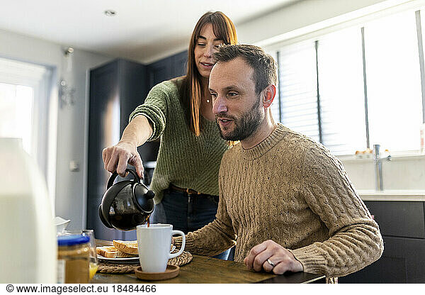 Man with woman pouring coffee in cup at table