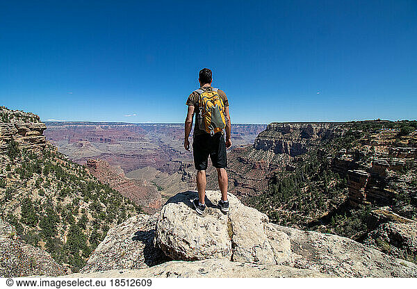 Man with yellow backpack at the edge of the Colorado canyon.