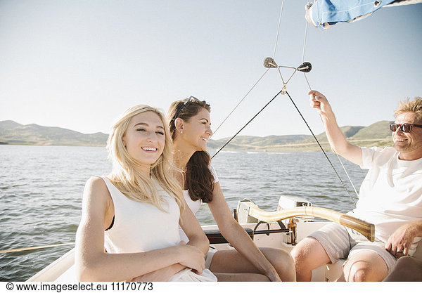 Man  woman and their blond teenage daughter on a sail boat.