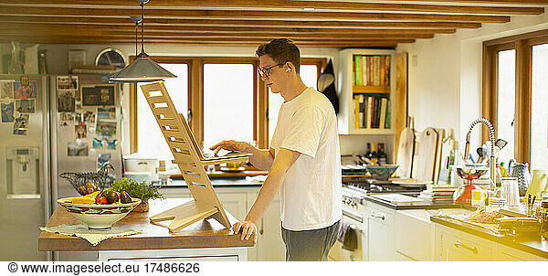 Man working at laptop stand desk in kitchen