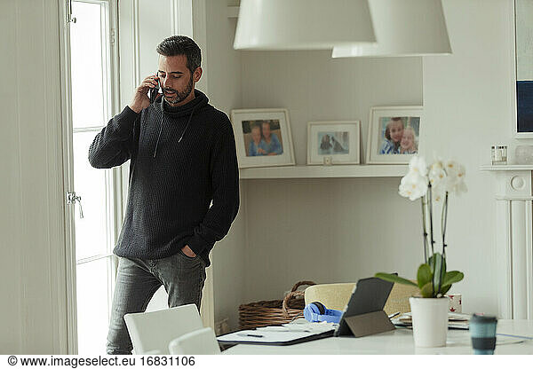 Man working from home talking on smart phone at window