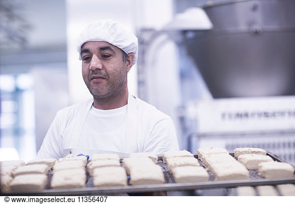 Man working in food production factory carrying tray