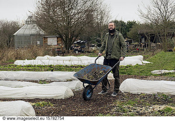 Man working in vegetable nursery  pushing wheelbarrow