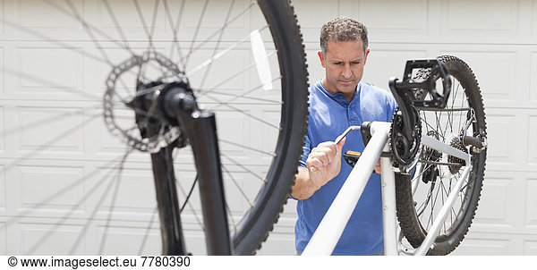 Man working on bicycle in driveway