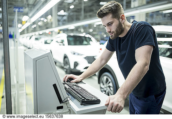 Man working on computer in modern car factory