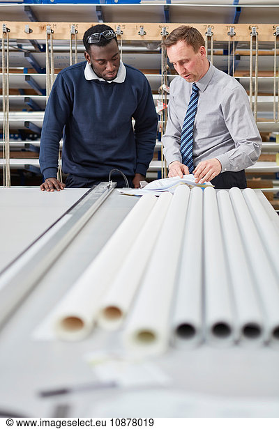 Manager and factory worker checking paperwork in roller blind factory