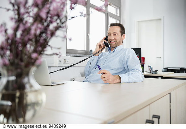 Manager in office using landline telephone