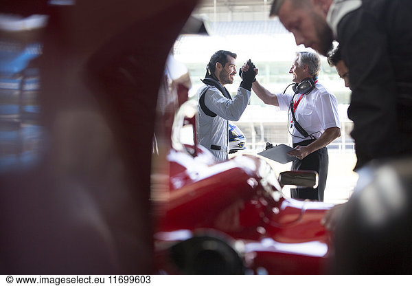 Manager und Formel-1-Rennwagenfahrer in der Reparaturwerkstatt