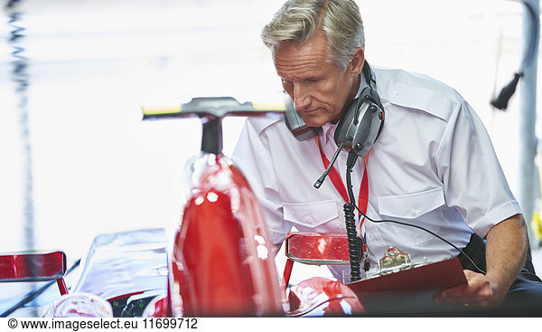 Manager with clipboard next to formula one race car