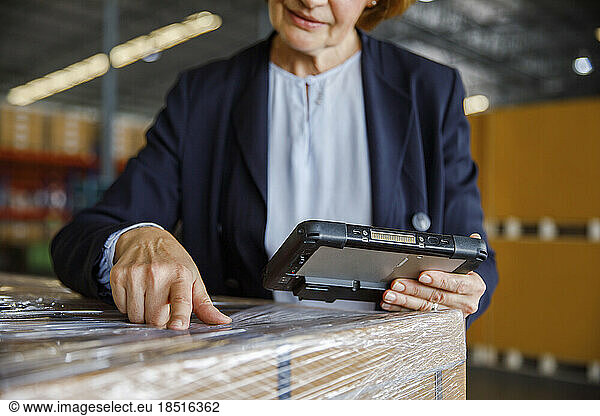 Manager with tablet PC examining in warehouse