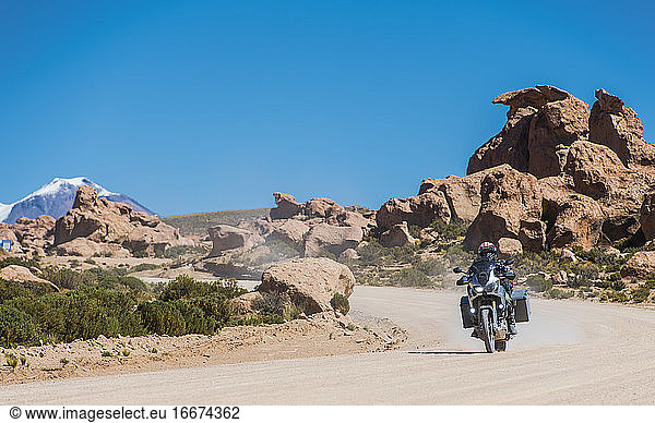 Mann auf Tourenmotorrad auf staubiger Straße in Bolivien