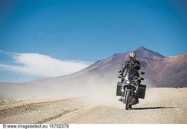 Mann auf Tourenmotorrad auf staubiger Straße in Bolivien