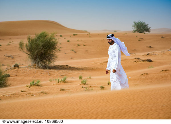 Mann aus dem Nahen Osten in traditioneller Kleidung zu Fuß in der Wüste  Dubai  Vereinigte Arabische Emirate
