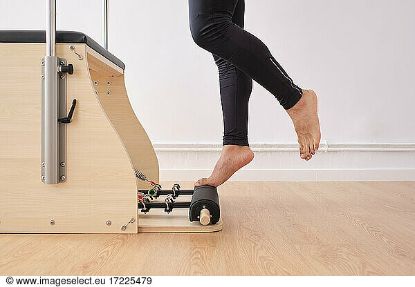 Mann balanciert auf einem Pilates-Stuhl im Fitnessraum