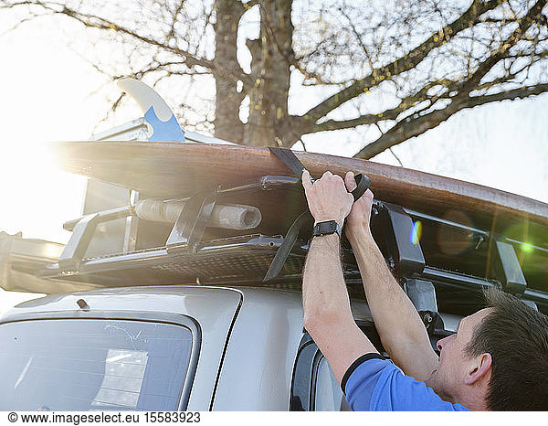 Mann befestigt Schaufelbrett auf dem Autodach