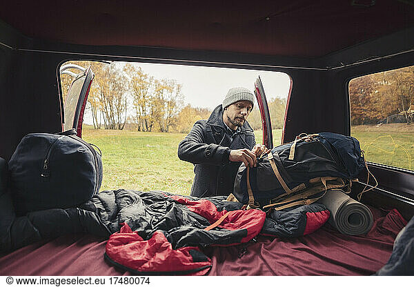 Mann beim Befestigen von Gepäckstücken im Campingbus beim Camping