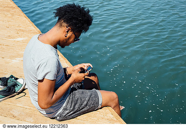 Mann benutzt Mobiltelefon am Wasserrand