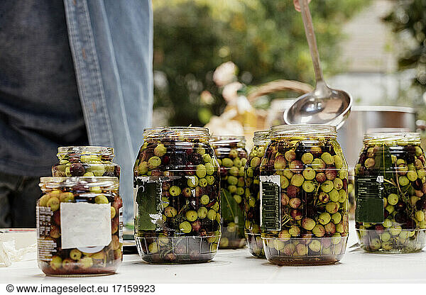 Mann bereitet Oliven in Gläsern vor