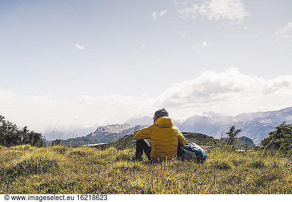 Mann betrachtet die Aussicht  während er auf einem Berg in Patagonien  Argentinien  Südamerika sitzt