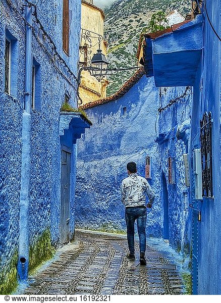 Mann  der in einer engen Straße in der Blauen Medina  Chefchaouen  Marokko  spazieren geht.
