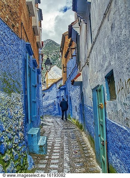 Mann  der in einer engen Straße in der Blauen Medina  Chefchaouen  Marokko  spazieren geht.