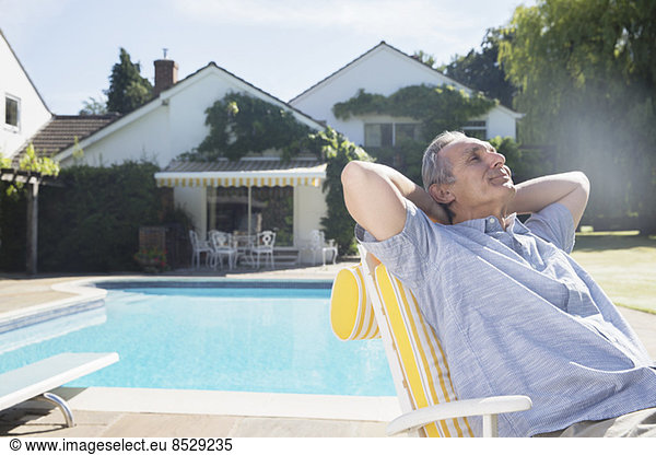 Mann entspannt im Liegestuhl am Pool