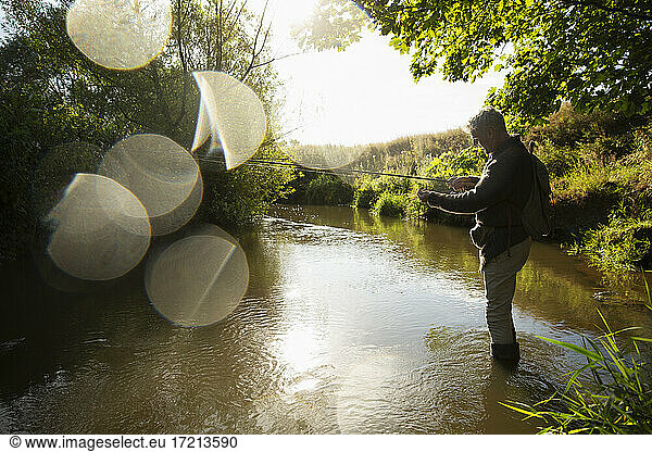 Mann Fliegenfischen am sonnigen idyllischen Fluss